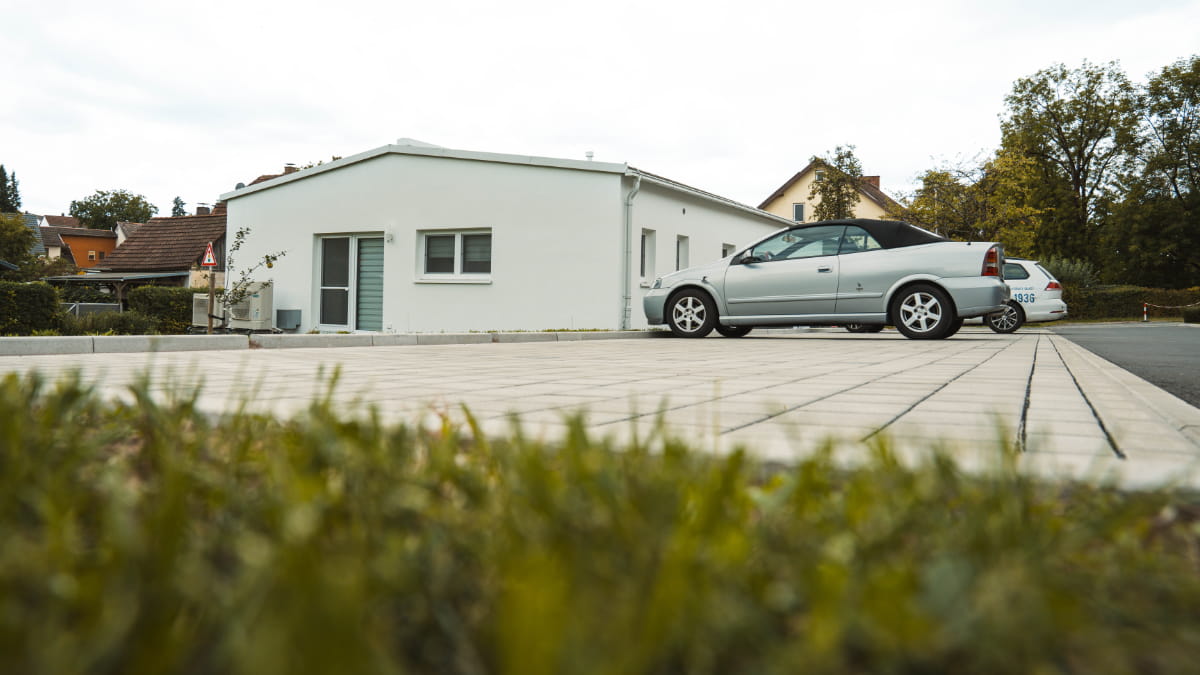Hell gepflasterter Parkplatz vor einer Zahnarztpraxis mit abgestellten Autos.