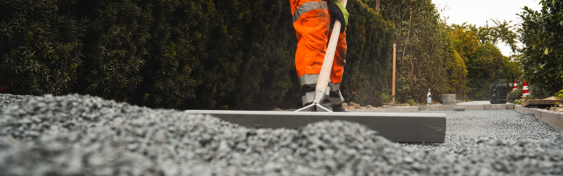 Bauarbeiter verteilt und glättet Schotter beim Ausbau des Heimatrings.