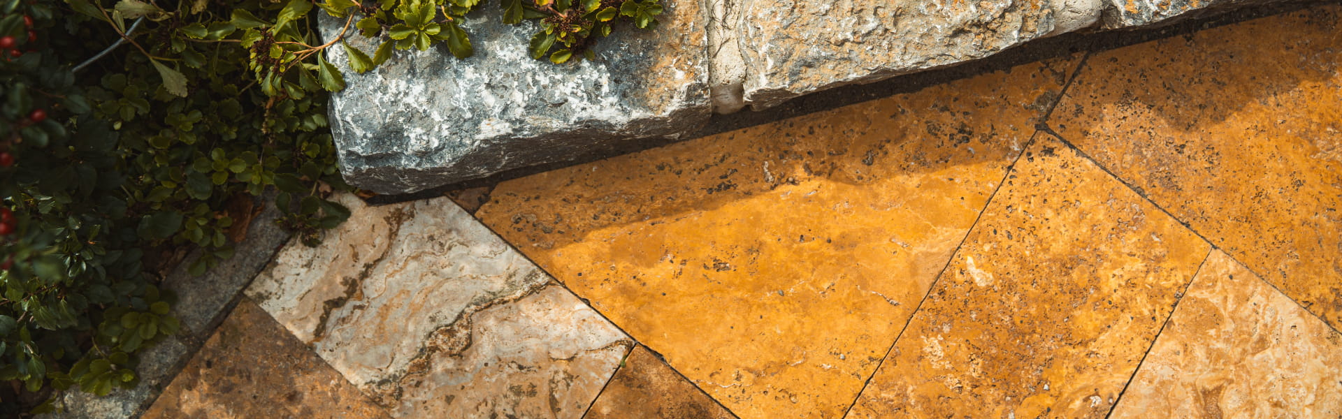 Detailansicht einer gepflasterten Terrasse mit Naturstein-Einfassung und angrenzender Bepflanzung.