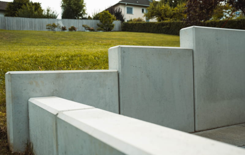 Abgestufte Beton-Randsteine als Einfassung zwischen gepflasterter Fläche und Rasen.